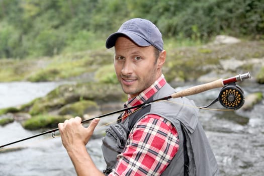 Closeup of fly-fisherman holding fishing rod in river