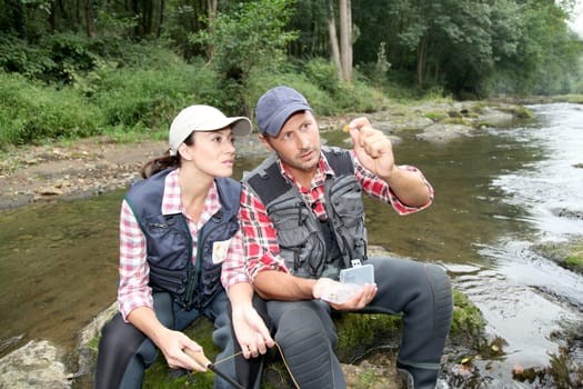 Man and woman fly fishing in river