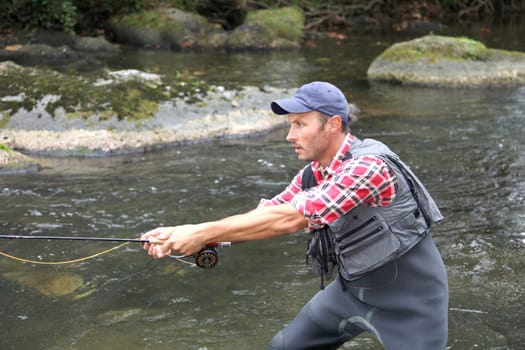 Fisherman in river with fly fishing line