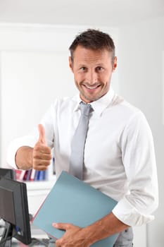 Happy businessman with thumb up in the office