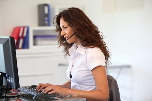 Businesswoman in front of computer with headset on