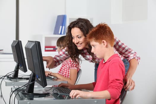 Teacher and children learning to use computer