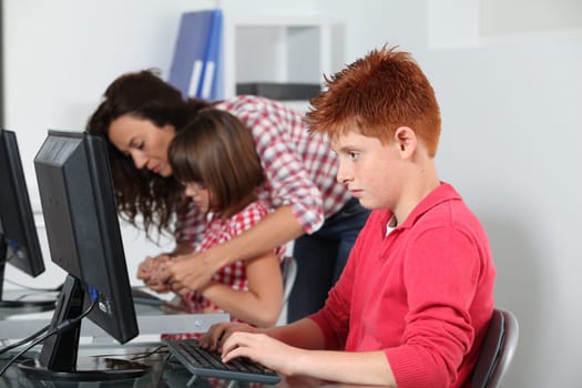 Teacher and children learning to use computer