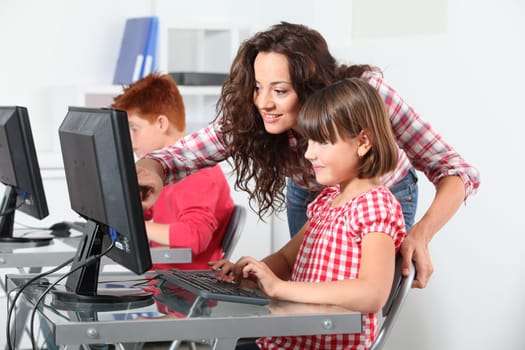 Teacher and children learning to use computer