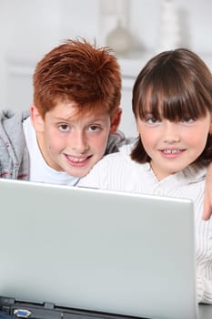 Young boy and girl at home with laptop