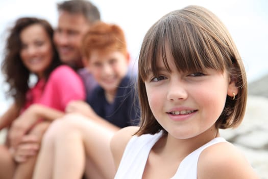 Little girl looking at camera and family in background