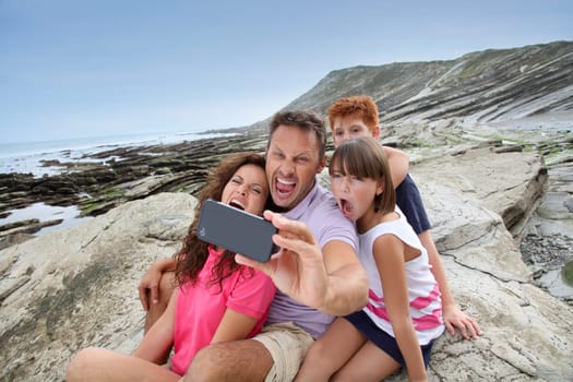 Father taking picture of the family in front of the sea