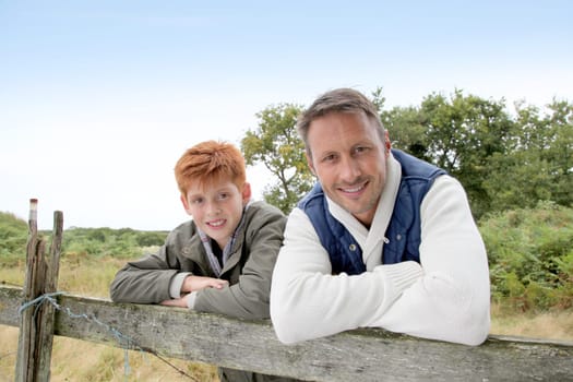 Father and son leaning on a fence