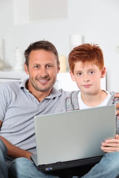 Man and child at home with laptop computer