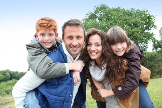 Parents doing piggyback to their children in countryside