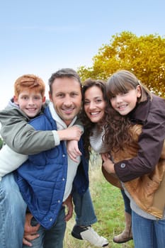Parents doing piggyback to their children in countryside