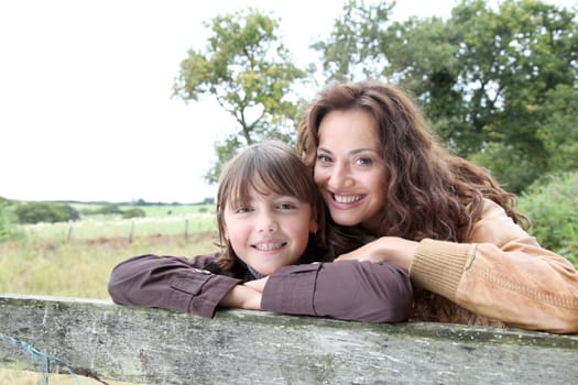 Mother and daughter leaning on a fence