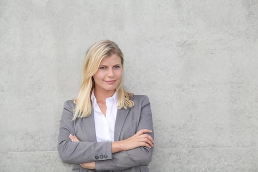 Blond businesswoman standing against a wall