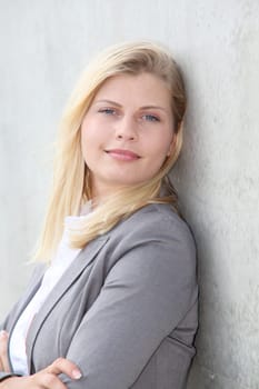 Blond businesswoman standing against a wall