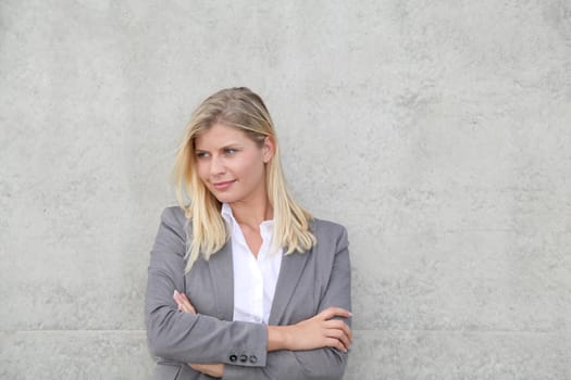 Blond businesswoman standing against a wall