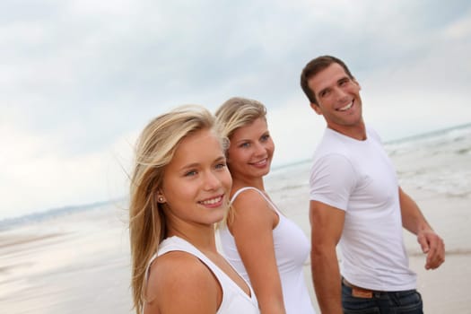 Family walking hand to hand on a sandy beach