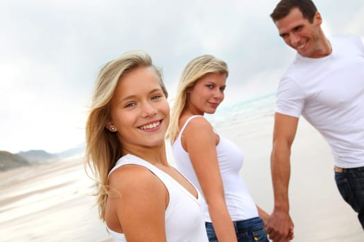 Family walking hand to hand on a sandy beach