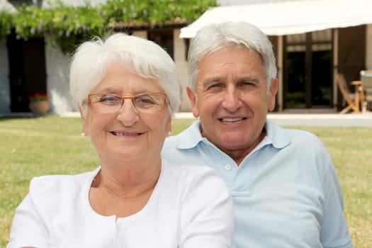 Senior couple sitting in front of a house