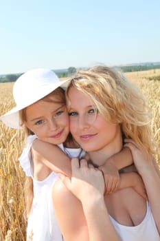 Mother and child in wheat field on sunny day