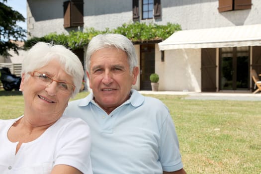 Senior couple sitting in front of a house