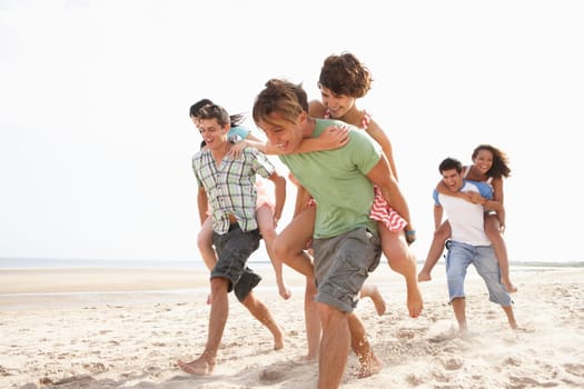 Group Of Friends Running Along Beach Together