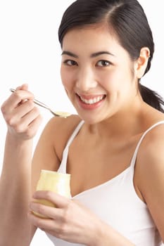 Young Woman Eating Yoghurt In Studio