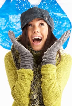 Young Woman Wearing Warm Winter Clothes And Hat Throwing Snowball In Studio