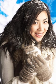 Young Woman Wearing Warm Winter Clothes Holding Snowball In Studio