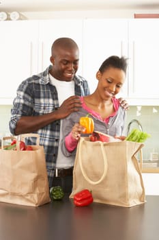 Young Couple Unpacking Shopping In Modern Kitchen