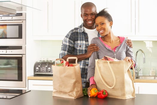 Young Couple Unpacking Shopping In Modern Kitchen