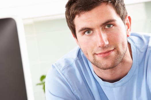 Young Man Using Computer In Modern Kitchen