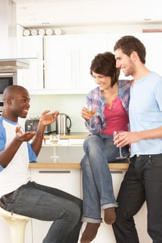 Group Of Young Friends Enjoying Glass Of Wine In Modern Kitchen