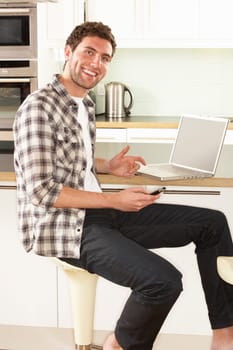 Young Man Relaxing Sitting In Kitchen Talking On Phone