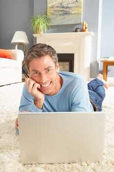 Man Using Laptop Relaxing Laying On Rug At Home
