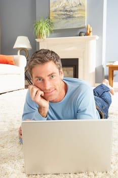 Man Using Laptop Relaxing Laying On Rug At Home