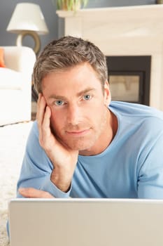 Man Using Laptop Relaxing Laying On Rug At Home