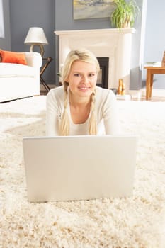 Woman Using Laptop Relaxing Laying On Rug At Home