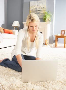 Woman Using Laptop Relaxing Sitting On Rug At Home