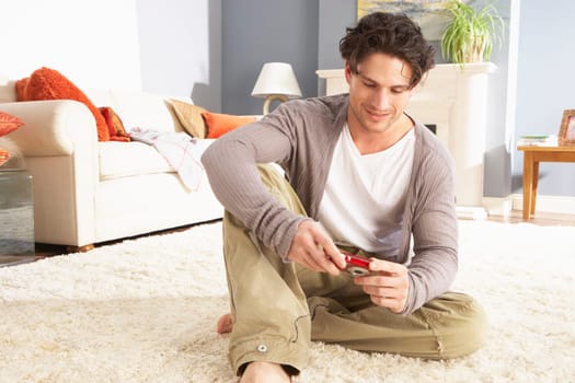 Young Man Looking At Photograph On Digital Camera At Home