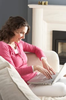 Woman Using Laptop Relaxing Sitting On Sofa At Home