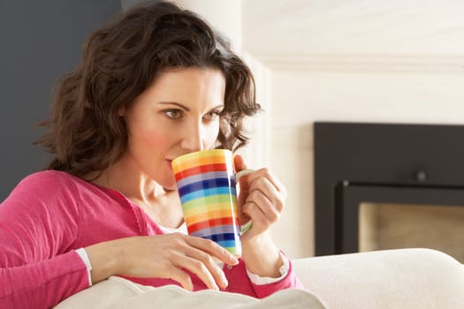 Woman Relaxing On Sofa At Home Drinking Cup Of Coffee
