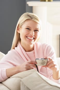 Young Woman Taking Photograph On Digital Camera At Home