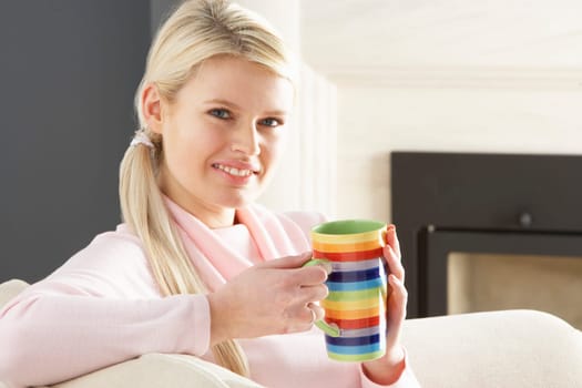 Woman Relaxing On Sofa At Home Drinking Cup Of Coffee