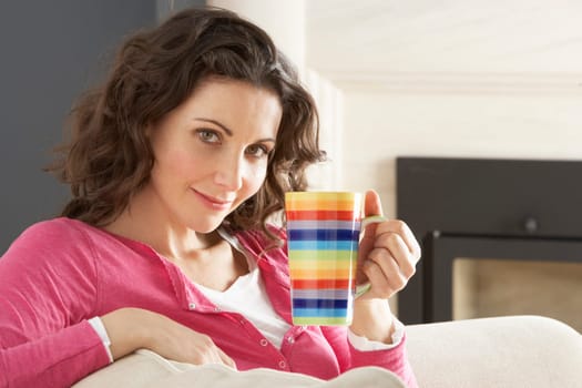 Woman Relaxing On Sofa At Home Drinking Cup Of Coffee