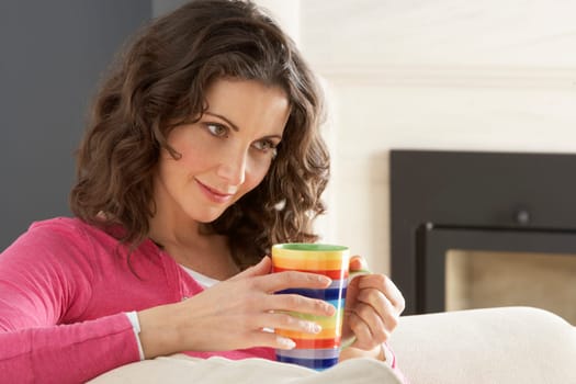 Woman Relaxing On Sofa At Home Drinking Cup Of Coffee