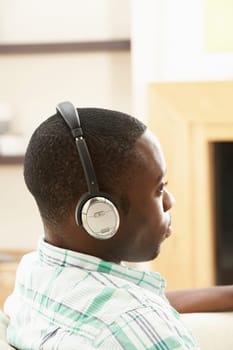 Young Man Relaxing Sitting On Sofa Listening to Music At Home On Headphones