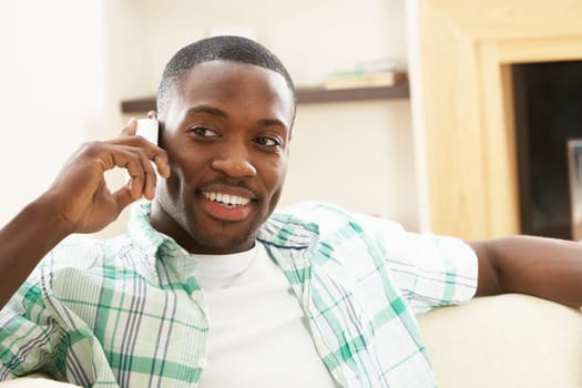 Young Man Relaxing Sitting On Sofa At Home Talking On Phone