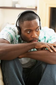 Young Man Relaxing Sitting On Sofa Listening to Music At Home On Headphones