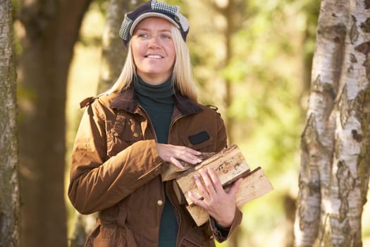 Woman Outdoors In Autumn Woodland Gathering Logs