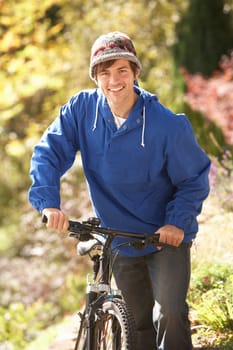 Portrait Of Young Man With Cycle In Autumn Park